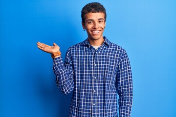 Young african amercian man wearing casual clothes smiling cheerful presenting and pointing with palm of hand looking at the camera.