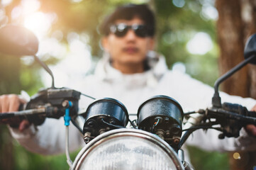 Close-up of a handsome man driving a motorcycle with nature with blurred background.