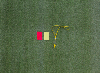 red and yellow referee soccer card isolated on green grass