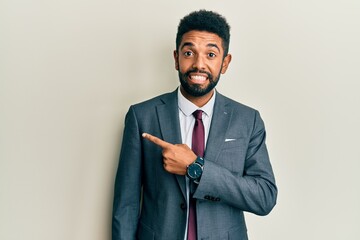 Handsome hispanic man with beard wearing business suit and tie pointing aside worried and nervous...