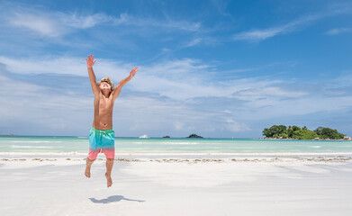 Fototapeta na wymiar Young boy jumping of joy on tropical beach, summer holiday concept