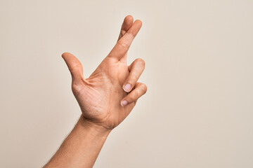 Hand of caucasian young man showing fingers over isolated white background gesturing fingers crossed, superstition and lucky gesture, lucky and hope expression