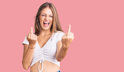 Young beautiful blonde woman wearing casual white tshirt showing middle finger doing fuck you bad...