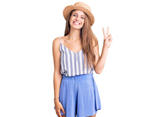 Obraz na płótnie Canvas Young beautiful blonde woman wearing summer hat showing and pointing up with fingers number two while smiling confident and happy.
