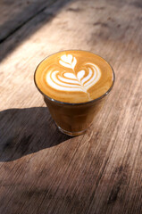 Hot latte coffee with heart shape latte art on dark brown old wood table at caff food and drink concept.
                               