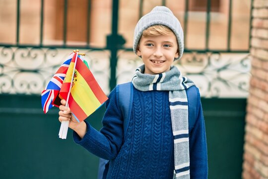 Adorable blond student kid smiling happy holding flags of different countries at the school.