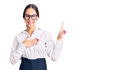 Beautiful brunette young woman wearing professional waitress apron smiling swearing with hand on...