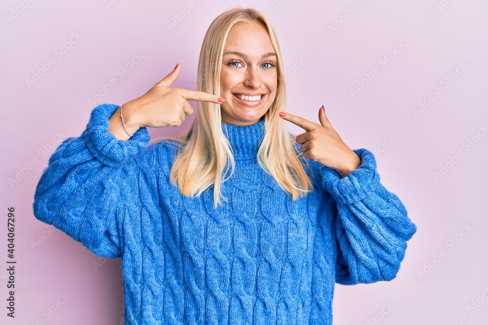 Canvas Prints young blonde girl wearing wool winter sweater smiling cheerful showing and pointing with fingers tee