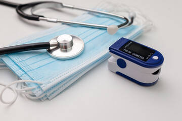 Pulse oximeter. Digital device, medical mask, on a white background, selective focus