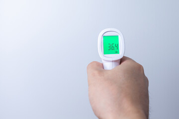 Hand with infrared thermometer on gray background
