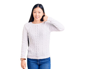Young beautiful chinese woman wearing casual sweater smiling doing phone gesture with hand and fingers like talking on the telephone. communicating concepts.