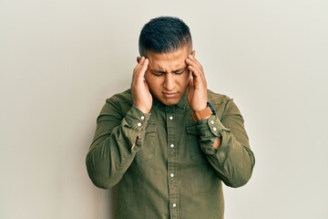 Young latin man wearing casual clothes with hand on head, headache because stress. suffering migraine.