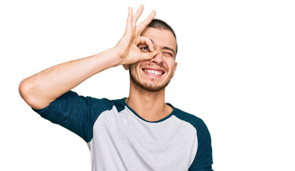 Hispanic young man wearing casual clothes smiling happy doing ok sign with hand on eye looking through fingers