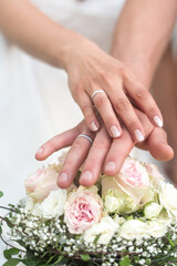Obraz na płótnie Canvas Brautpaar hält Hände mit Eheringen über den Brautstrauß aus weißen Rosen