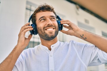 Handsome man with beard wearing headphones and enjoying listening to music outdoors