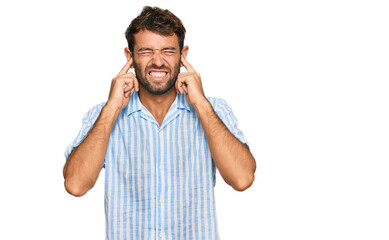 Naklejka premium Handsome young man with beard wearing casual fresh shirt covering ears with fingers with annoyed expression for the noise of loud music. deaf concept.