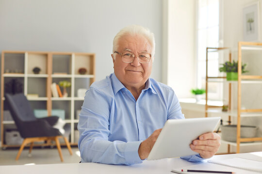 Happy senior man shopping online, managing budget and reading news using tablet.