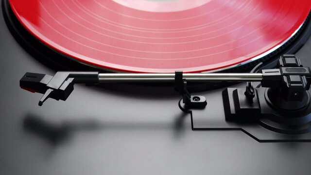 Placing red vinyl record on a turntable. Spinning red LP on a turntable. Proces of preparing album for listening on a gramophone