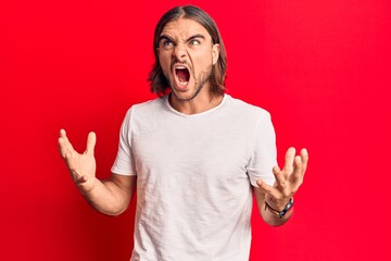 Fototapeta premium Young handsome man wearing casual clothes crazy and mad shouting and yelling with aggressive expression and arms raised. frustration concept.