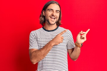 Fototapeta premium Young handsome man wearing casual clothes smiling and looking at the camera pointing with two hands and fingers to the side.