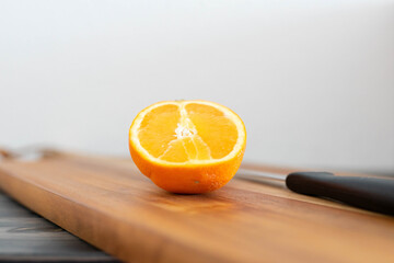 Orange auf einem Küchenbrett aus Holz mit einem Messer