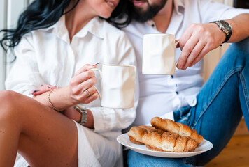 Couple in love in the kitchen. Romantic man and woman have breakfast with croissants and coffee in...