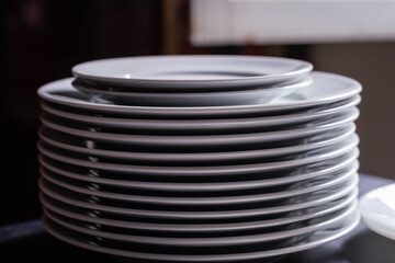 stack or mountain of large white porcelain plates with two smaller ones on top