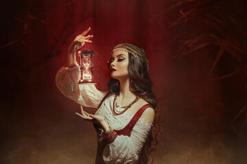 Fantasy woman creates magic. Gypsy girl witch holding magical hourglass in hands. Photo levitation....