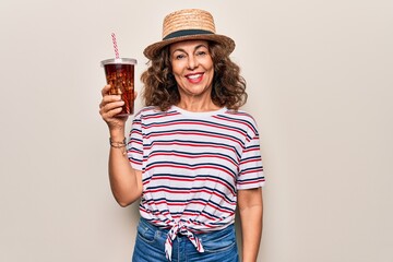 Middle age brunette woman on summer hat drinking fresh cola refeshment over isolated background...