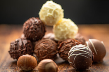 Mixed chocolate gourmet with nuts arranged in stack and photographed in white and brown wooden boards.