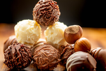 Mixed chocolate gourmet with nuts arranged in stack and photographed in white and brown wooden boards.