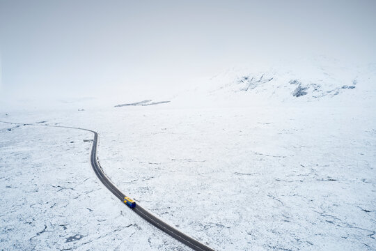 Aerial view of A82 road through Rannoch Moor and Black Mount covered in snow during winter