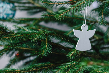 Christmas tree toy white wooden angel hanging on a spruce branch