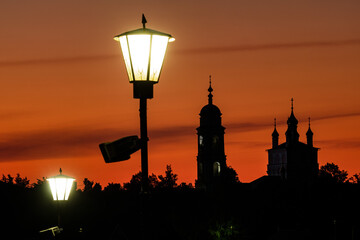 The silhouette of an Orthodox church against the background of a shining gold bright orange sky.