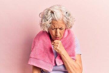 Senior grey-haired woman wearing sportswear and towel feeling unwell and coughing as symptom for cold or bronchitis. health care concept.