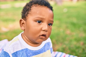 Adorable african american chubby toddler sitting on the grass at the park.