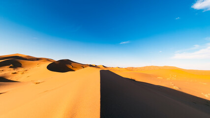 Plakat (Selective focus) Stunning view of some sand dunes illuminated at sunset. Merzouga, Morocco. Natural background with copy space.