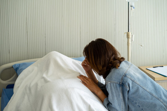 Asian woman daughter crying mourning on death patient on hospital bed 