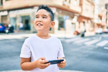 Fototapeta premium Adorable boy smiling happy using smartphone at street of city.