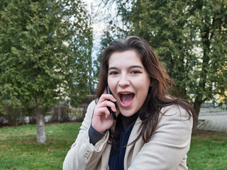 Expression of joyful emotions. The girl speaks on the phone and smiles sincerely.