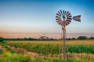 Vintage windmill at sunset with cornfield. - Powered by Adobe