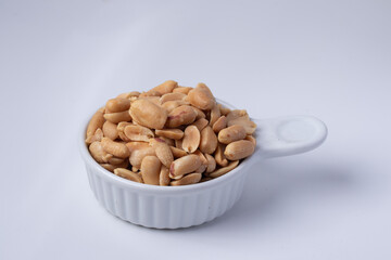 Peanuts in a white ceramic cup on a white background