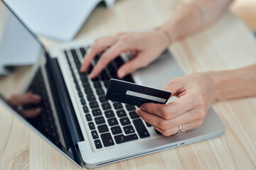 Woman holding credit card and purchasing online with modern laptop.