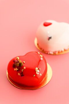 A cake in heart shape. Two cupcakes in the shape of a heart on a pink background. Valentine's Day. Vertical photo