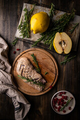 Raw duck breast, quince, rosemary and dried cranberries on wooden table.