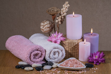 Composition spa, beauty treatment and wellness background with massage stone, flowers, towels and burning candles. 