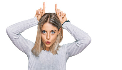 Fototapeta premium Beautiful blonde woman wearing casual clothes doing funny gesture with finger over head as bull horns