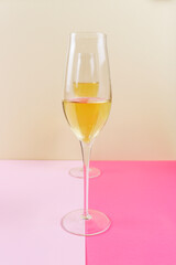 Two glasses of champagne wine on a light and dark pink color.
