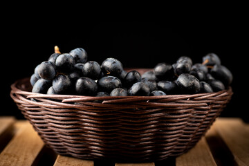 Dark grape in the basket on a black background