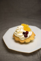 tartlets made of dough with cream and fruit on a white plate
